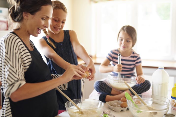 Shot of two little girls baking with their mother in the kitchen