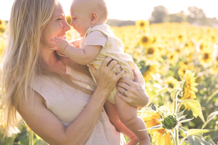 mom and baby smiling in a sunflower field