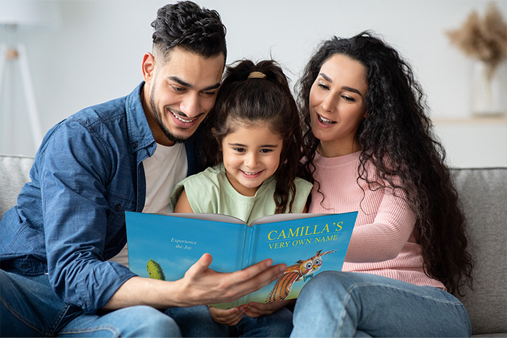 Mom, dad, and child sit on the couch and read the personalized children's book "My Very Own Name" together